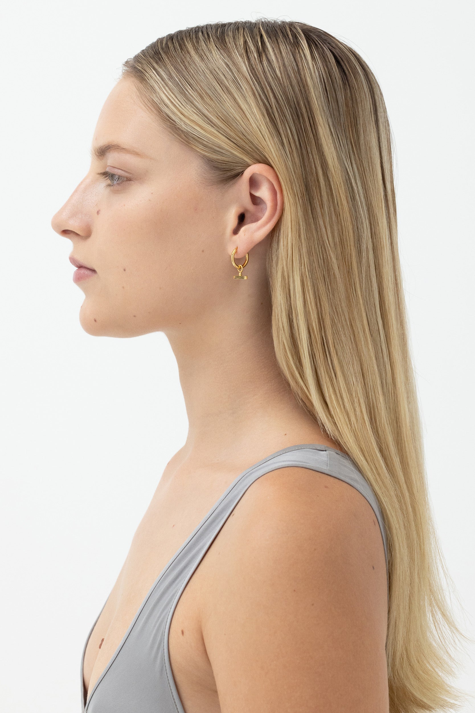 Model wearing Chloe Sleeper Hoops in 14k gold vermeil, showcasing side profile