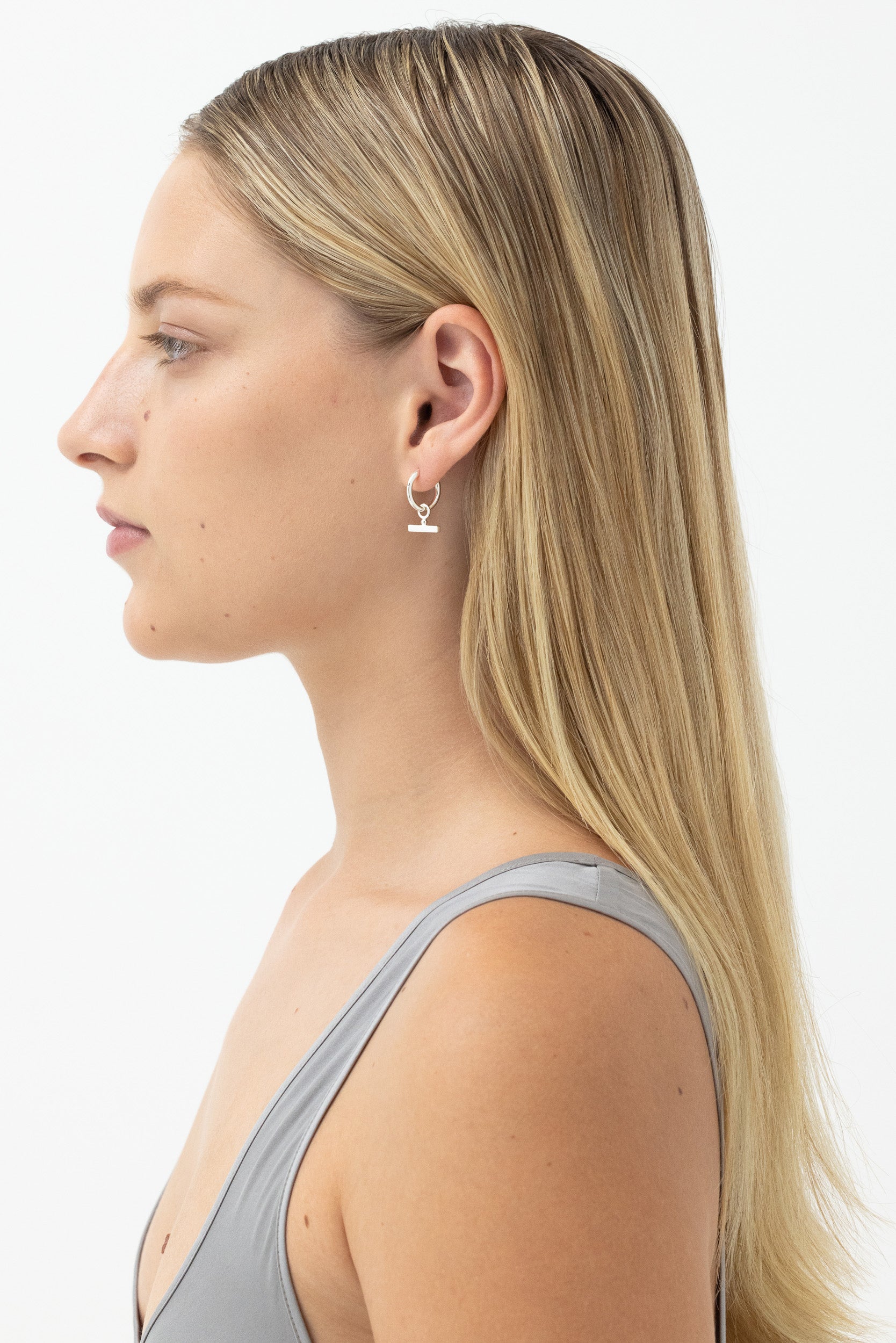 Model wearing Chloe Sleeper Hoops in Sterling Silver, showcasing side profile