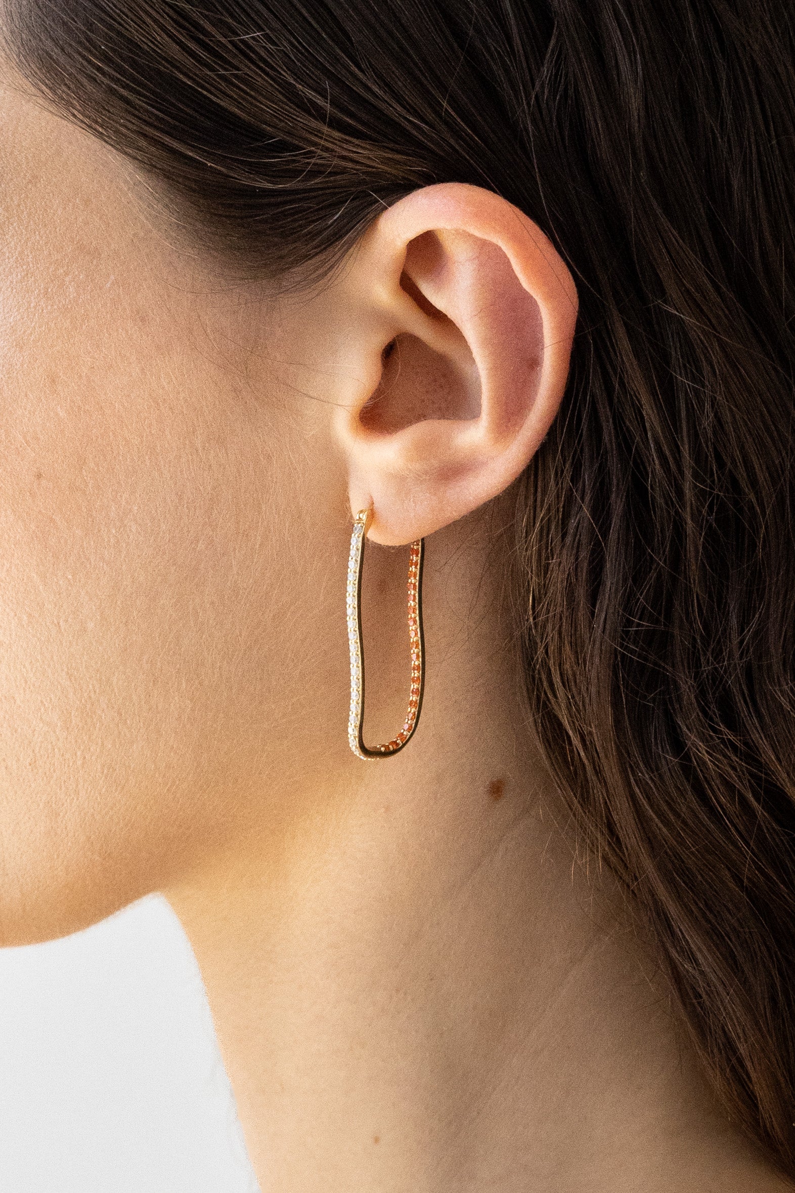 Side profile of model wearing 14k vermeil hoops with vibrant gemstones